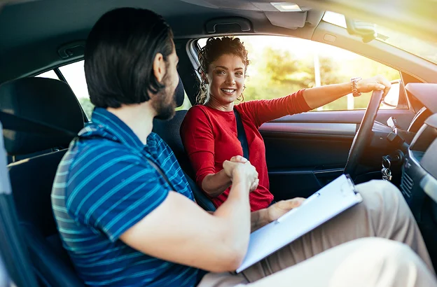 Femme conductrice souriante serrant la main de son instructeur avec un presse-papiers à Villeneuve‑sur‑Lot et à Saint‑Sylvestre‑sur‑Lot dans le Lot‑et‑Garonne 47