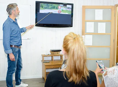 Un instructeur de conduite pointe une télévision avec un bâton, tandis que des élèves regardent à Villeneuve‑sur‑Lot et à Saint‑Sylvestre‑sur‑Lot dans le Lot‑et‑Garonne 47