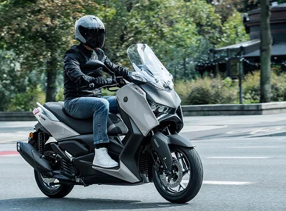 Un homme conduit un scooter Yamaha XMAX blanc et gris sur la route à Villeneuve‑sur‑Lot et à Saint‑Sylvestre‑sur‑Lot dans le Lot‑et‑Garonne 47