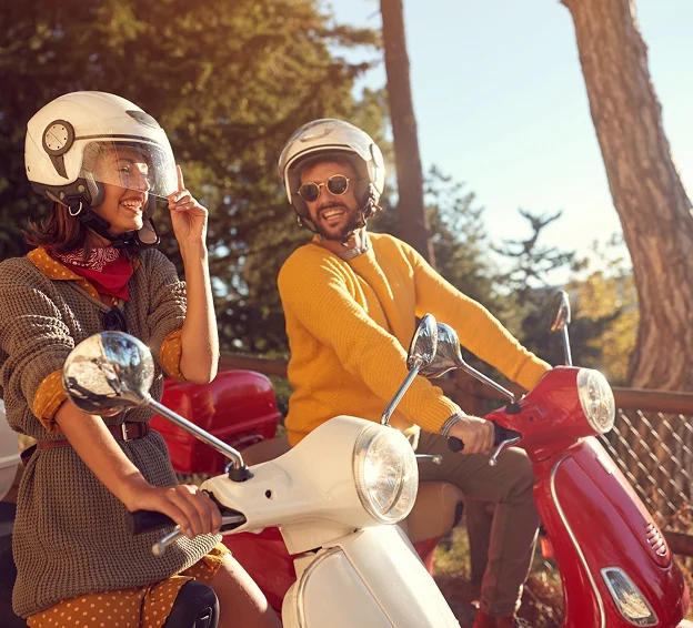 Couple souriant en casques, chacun sur un scooter, profitant du plein air à Villeneuve‑sur‑Lot et à Saint‑Sylvestre‑sur‑Lot dans le Lot‑et‑Garonne 47